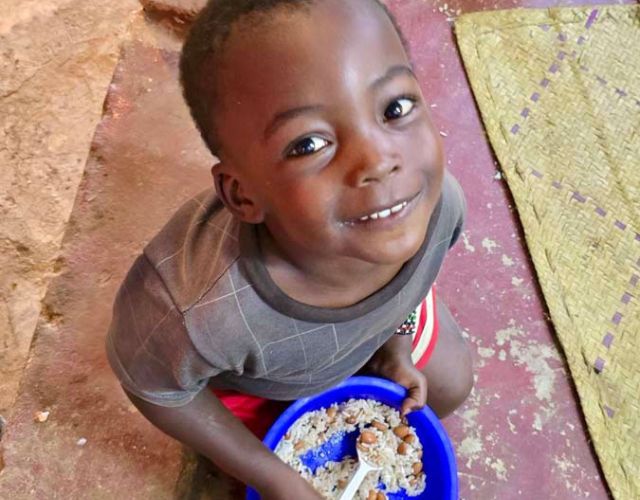 kid eats rice in dish